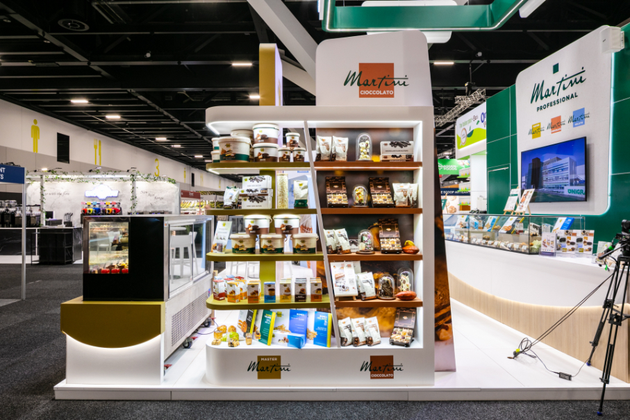 Custom exhibition display plinth with gold and white fabricated base, integrated refrigerated display case, and large-format lifestyle graphic panel built for Master Martini at Restaurant & Foodservice Show Australia 2026