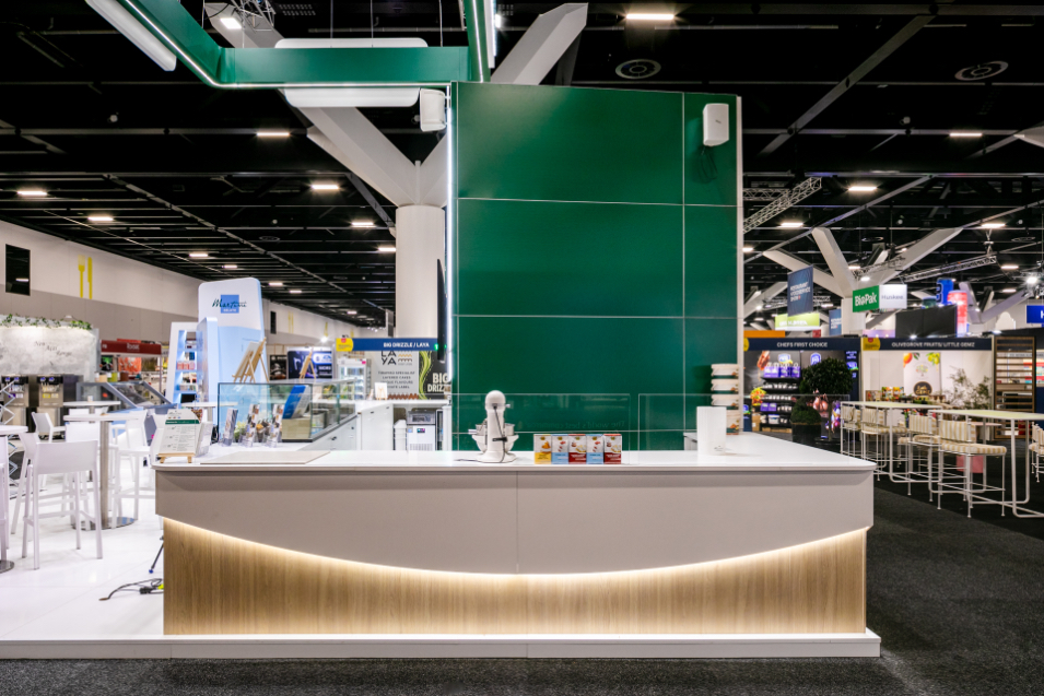 Bespoke large-format exhibition product display wall with full-height lifestyle photography graphics and custom illuminated shelving built for OraSì at Restaurant & Foodservice Show Australia 2026